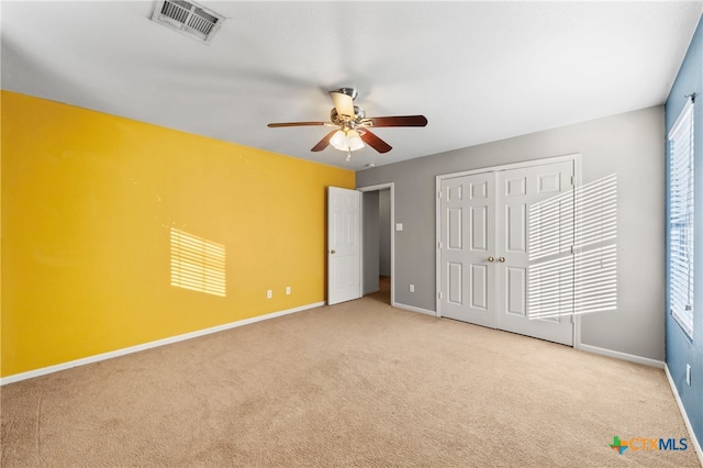 unfurnished bedroom with ceiling fan, light colored carpet, and a closet