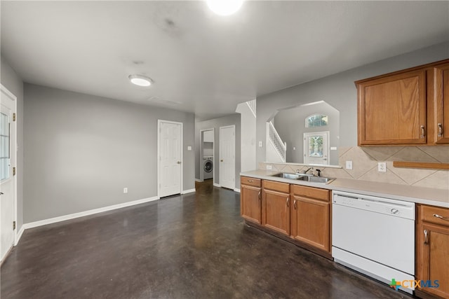 kitchen featuring washer / dryer, white dishwasher, tasteful backsplash, and sink