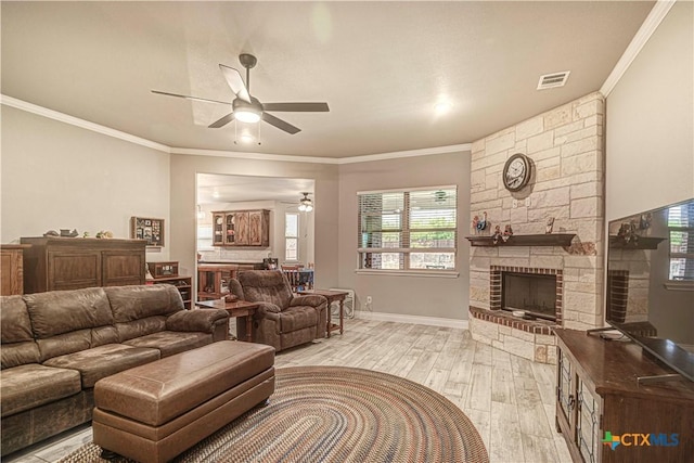 living room with ceiling fan, a large fireplace, ornamental molding, and light hardwood / wood-style floors