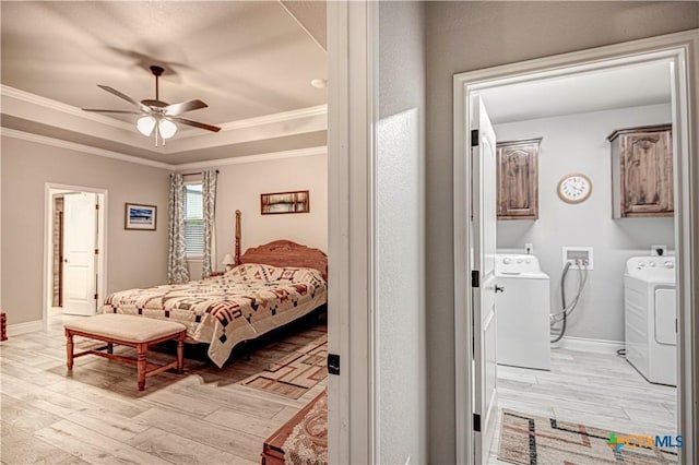 bedroom featuring separate washer and dryer, a tray ceiling, light hardwood / wood-style floors, and crown molding