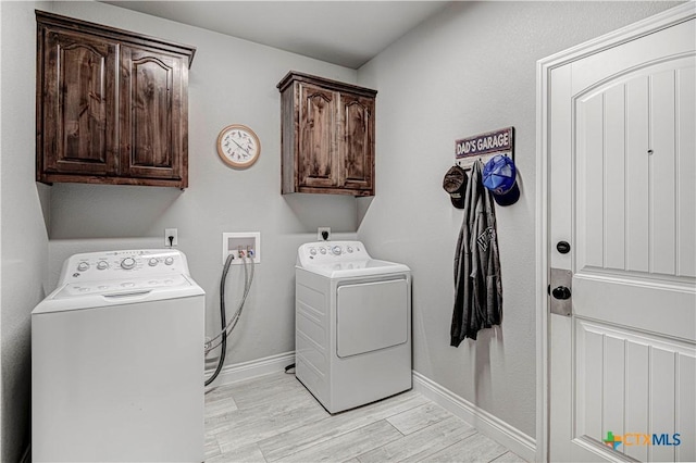 clothes washing area with light hardwood / wood-style flooring, washer and clothes dryer, and cabinets