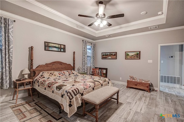 bedroom with crown molding, light hardwood / wood-style flooring, a raised ceiling, and ceiling fan