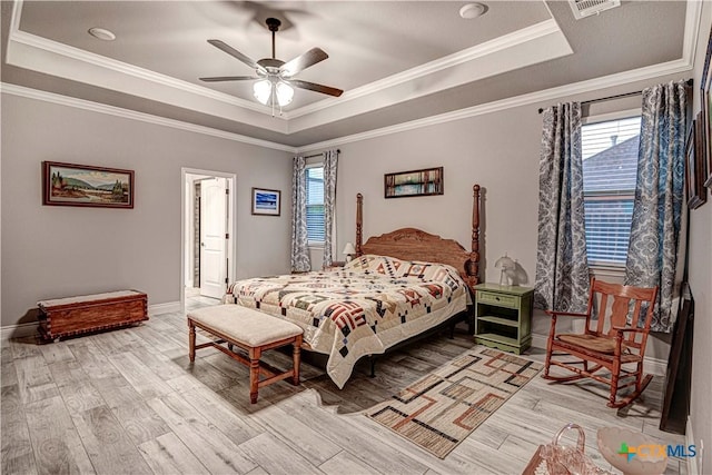 bedroom with crown molding, ceiling fan, a tray ceiling, and light hardwood / wood-style flooring