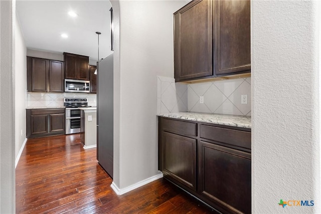 210 Mancos Dr, Georgetown, TX 78626 - kitchen featuring appliances with stainless steel finishes, dark brown cabinets, tasteful backsplash, dark wood-style flooring, and light stone countertops