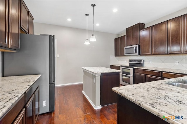 210 Mancos Dr, Georgetown, TX 78626 - kitchen with stainless steel appliances, dark wood finished floors, tasteful backsplash, a kitchen island, and dark brown cabinetry