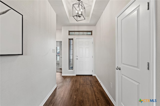 entryway featuring dark hardwood / wood-style floors, a chandelier, and a tray ceiling