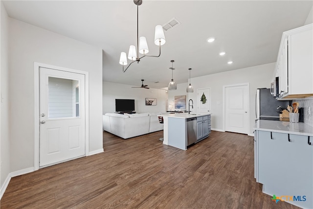 kitchen with white cabinetry, decorative light fixtures, sink, an island with sink, and dark wood-type flooring