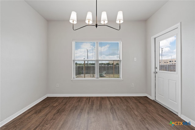 unfurnished dining area with a wealth of natural light, a chandelier, and dark hardwood / wood-style floors