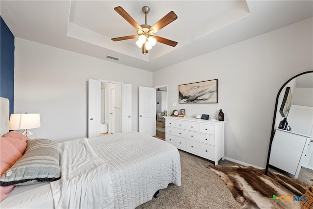 bedroom featuring dark colored carpet, ceiling fan, and a tray ceiling