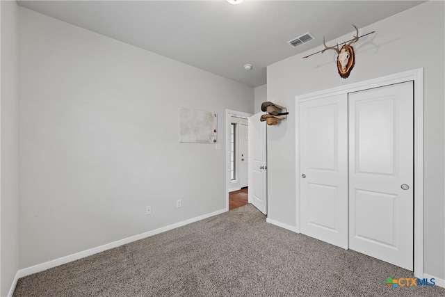 unfurnished bedroom featuring dark colored carpet and a closet