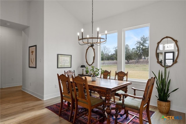 dining space featuring baseboards, high vaulted ceiling, an inviting chandelier, and light wood finished floors