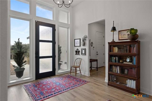 entrance foyer featuring baseboards, a notable chandelier, and wood finished floors