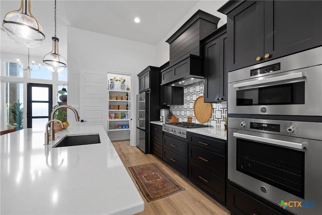 kitchen with dark cabinets, light countertops, stainless steel appliances, and a sink