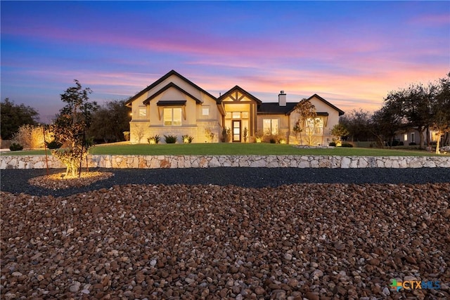 view of front of property featuring a lawn, a chimney, and stucco siding