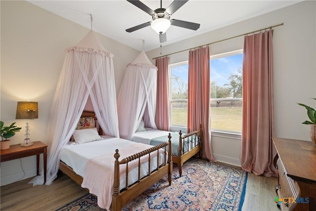 bedroom featuring wood finished floors, baseboards, and ceiling fan