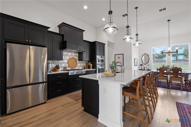 kitchen with stainless steel appliances, visible vents, dark cabinetry, and light countertops