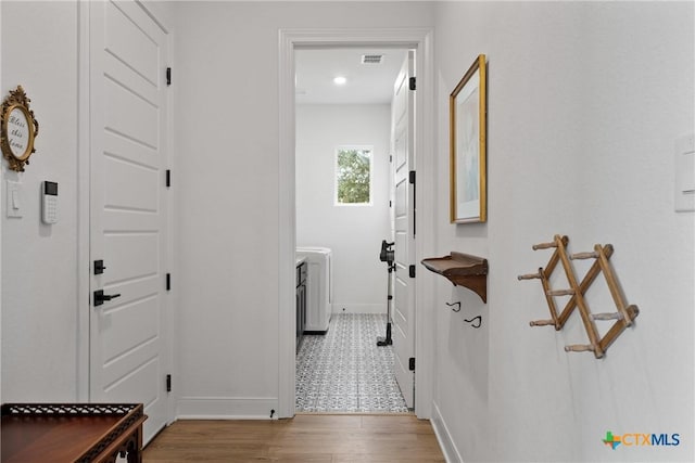 clothes washing area with visible vents, baseboards, wood finished floors, and laundry area