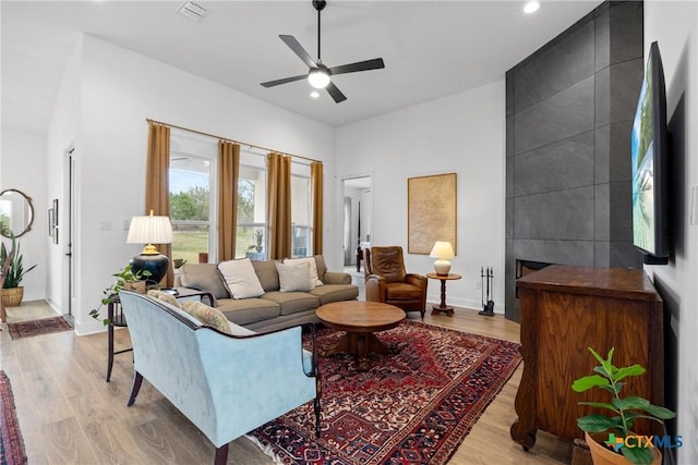 living area featuring baseboards, visible vents, light wood finished floors, and a large fireplace