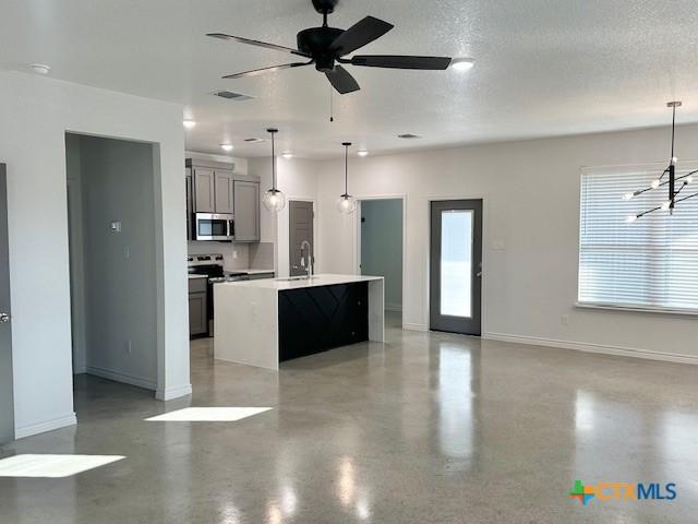 kitchen with a kitchen island with sink, sink, hanging light fixtures, and ceiling fan