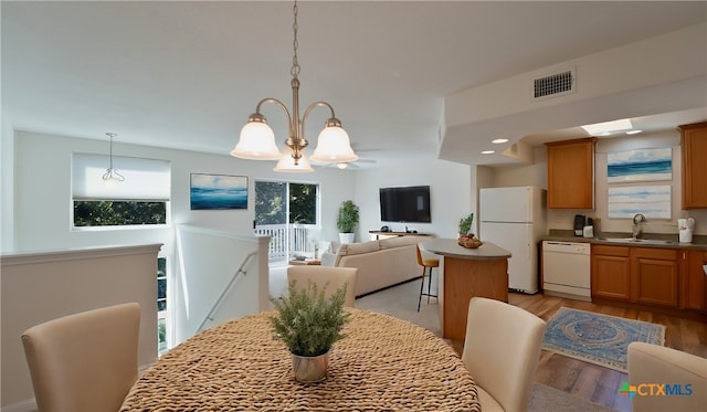 dining space featuring an inviting chandelier, sink, and light wood-type flooring