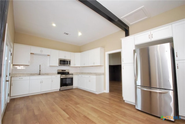 215 E Gonzales St, Yoakum, TX 77995 - kitchen featuring stainless steel appliances, white cabinets, backsplash, a sink, and visible vents