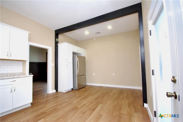 215 E Gonzales St, Yoakum, TX 77995 - kitchen with baseboards, light wood-style flooring, freestanding refrigerator, backsplash, and white cabinetry