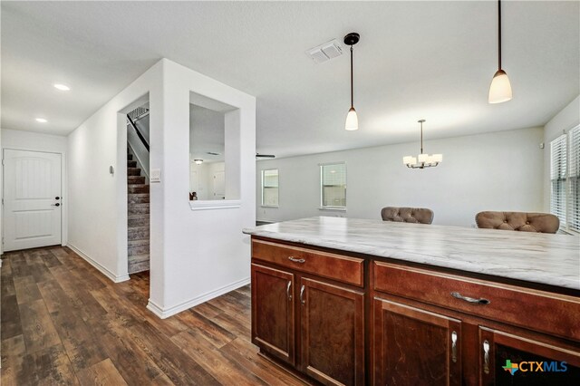 kitchen featuring pendant lighting, dark hardwood / wood-style flooring, light stone countertops, and a chandelier