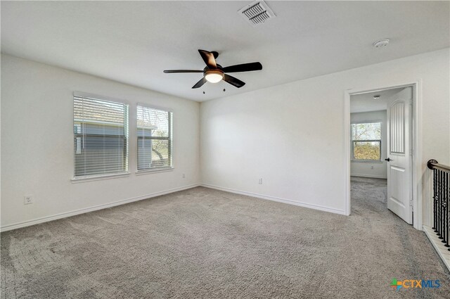 empty room with ceiling fan, light carpet, and a wealth of natural light