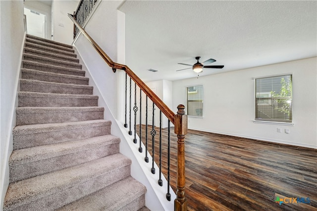 staircase featuring ceiling fan, a healthy amount of sunlight, wood-type flooring, and a textured ceiling