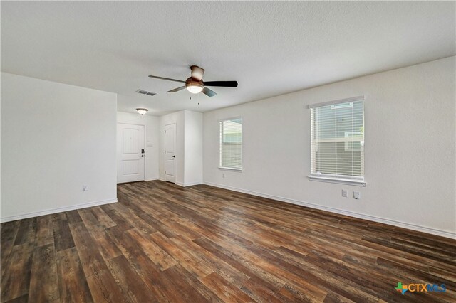 empty room with ceiling fan, dark wood-type flooring, and a textured ceiling