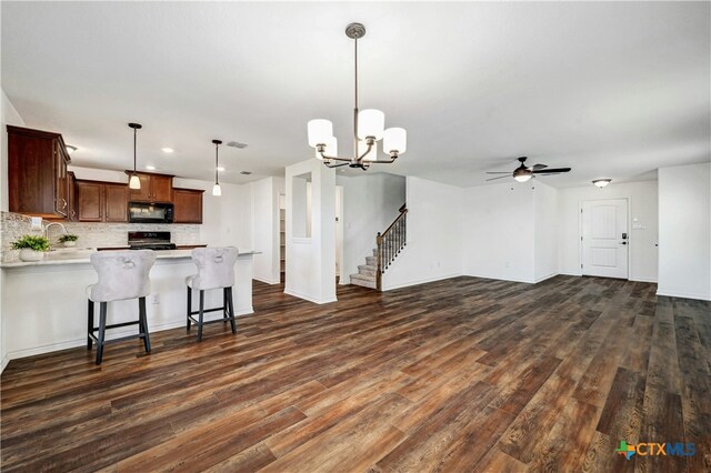 kitchen with black appliances, dark hardwood / wood-style flooring, hanging light fixtures, and ceiling fan with notable chandelier