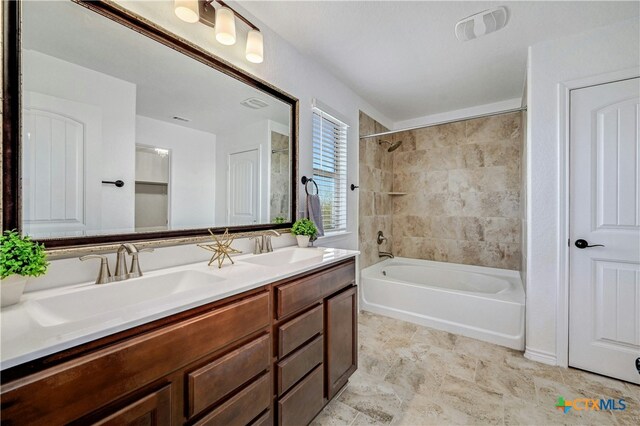 bathroom with tiled shower / bath combo and vanity