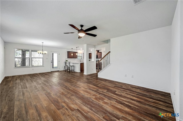 unfurnished living room with dark hardwood / wood-style flooring and ceiling fan with notable chandelier