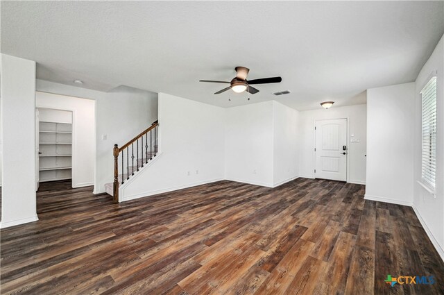 unfurnished living room with built in shelves, ceiling fan, and dark hardwood / wood-style floors