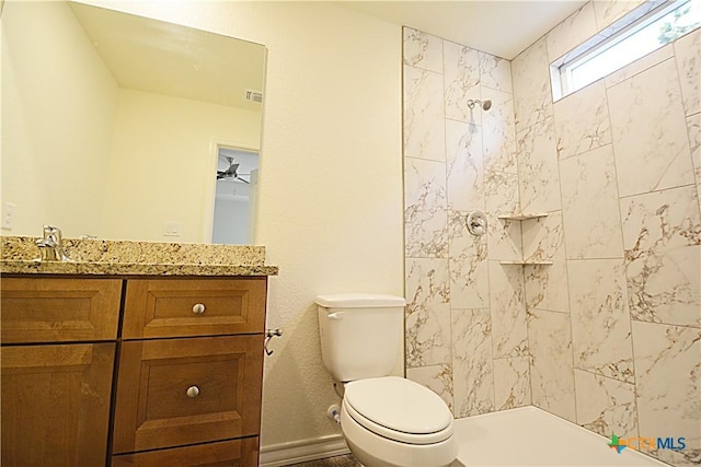 bathroom with vanity, toilet, and tiled shower