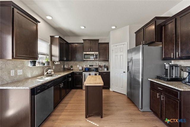 kitchen with light wood-type flooring, stainless steel appliances, dark brown cabinets, and a center island