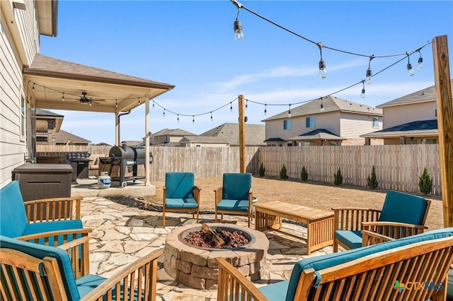 view of patio featuring an outdoor fire pit, a residential view, a ceiling fan, and a fenced backyard