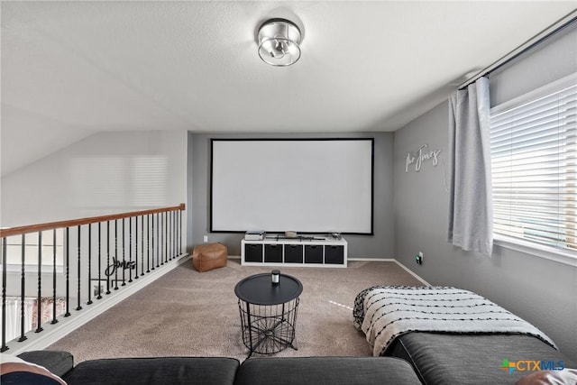 carpeted home theater featuring vaulted ceiling and baseboards