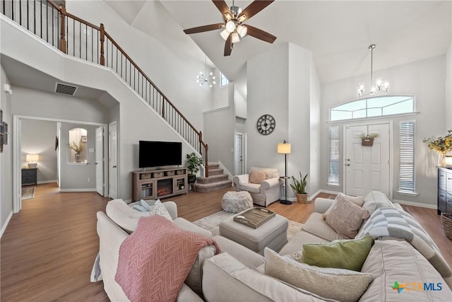 living area with baseboards, visible vents, wood finished floors, stairs, and a chandelier