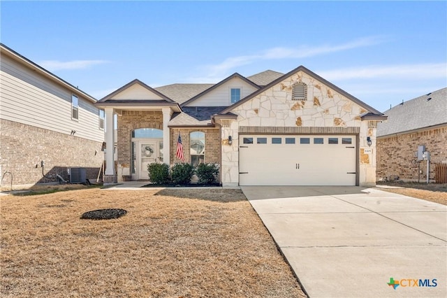 view of front of home featuring a garage, brick siding, a shingled roof, concrete driveway, and stone siding