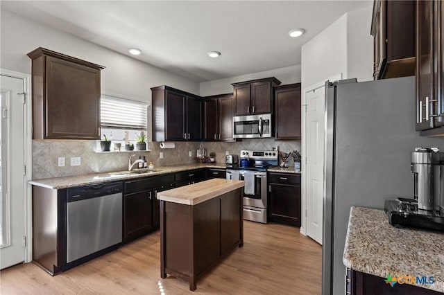 kitchen with a kitchen island, stainless steel appliances, dark brown cabinets, wooden counters, and a sink