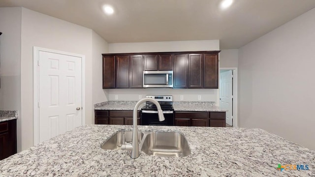 kitchen featuring light stone counters, sink, dark brown cabinetry, and stainless steel appliances