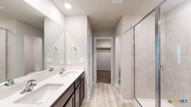 bathroom with hardwood / wood-style floors, vanity, a shower with shower door, and toilet