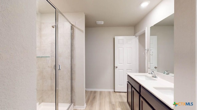 bathroom featuring vanity, wood-type flooring, and a shower with door