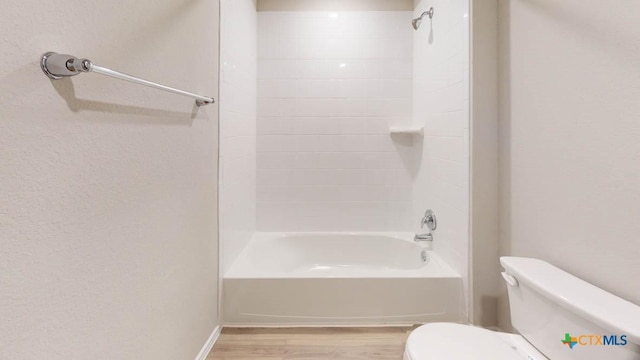 bathroom with wood-type flooring, tiled shower / bath combo, and toilet