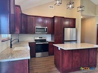 133 E Mcanelly St, Lometa, TX 76853 - kitchen with appliances with stainless steel finishes, dark wood finished floors, a kitchen island, high vaulted ceiling, and pendant lighting