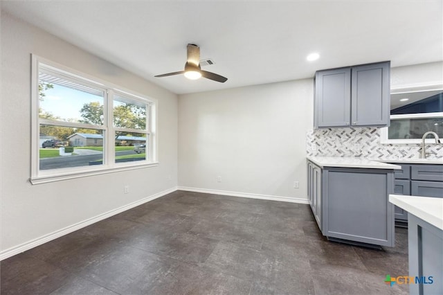 kitchen with backsplash, gray cabinets, ceiling fan, and sink