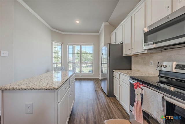 7624 Copper Creek Trl, Temple, TX 76502 - kitchen featuring appliances with stainless steel finishes, dark wood-style flooring, a kitchen island, tasteful backsplash, and ornamental molding