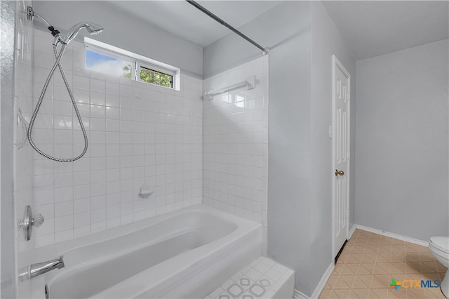 bathroom featuring tile patterned flooring, tiled shower / bath combo, and toilet