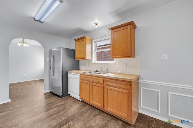 kitchen with sink, hardwood / wood-style floors, dishwasher, stainless steel fridge, and decorative backsplash